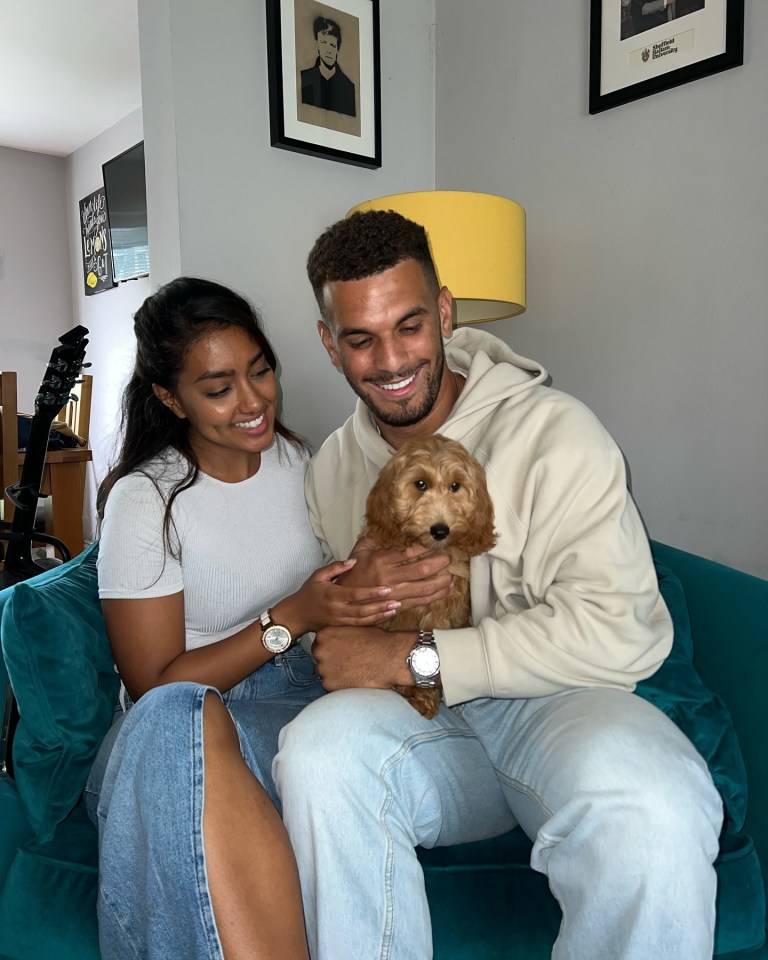 a man and woman sit on a couch holding a small dog