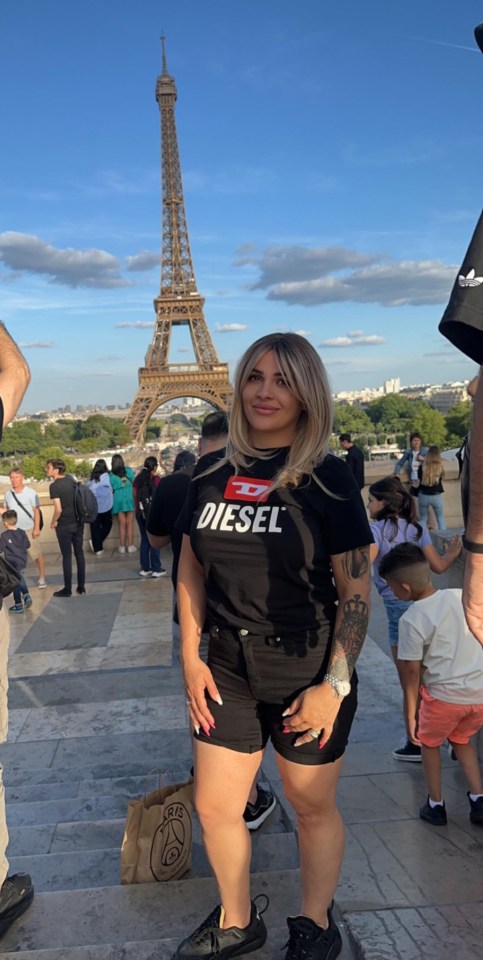 a woman wearing a black diesel shirt stands in front of the eiffel tower