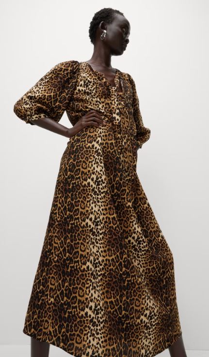 a woman is wearing a leopard print dress and earrings .