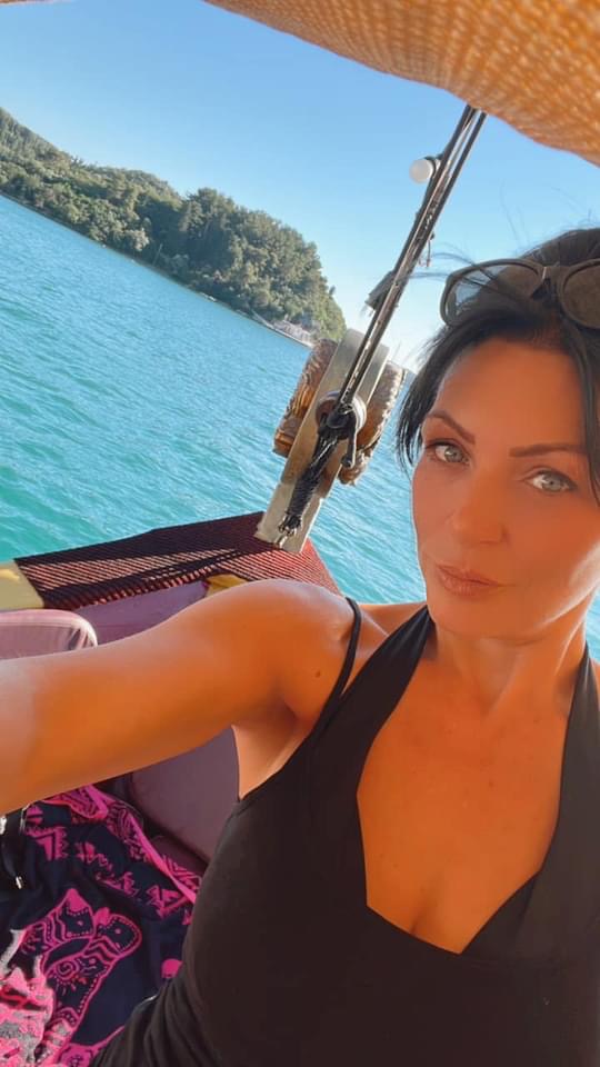 a woman in a black tank top is sitting on a boat in the water