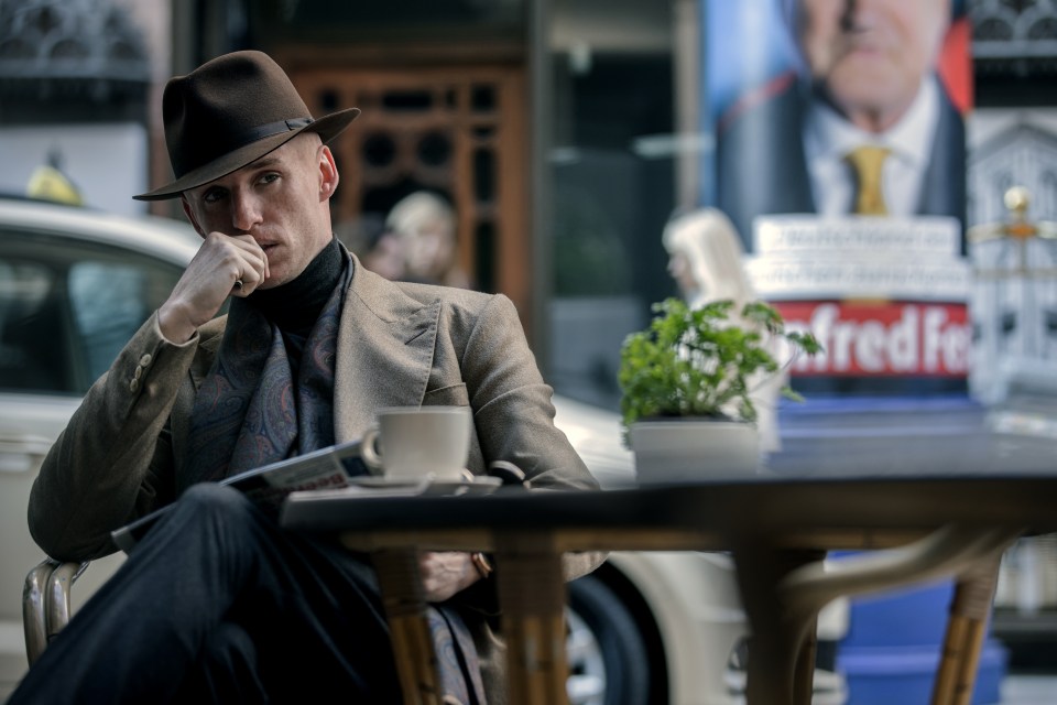 a man sits at a table in front of a sign that says frede