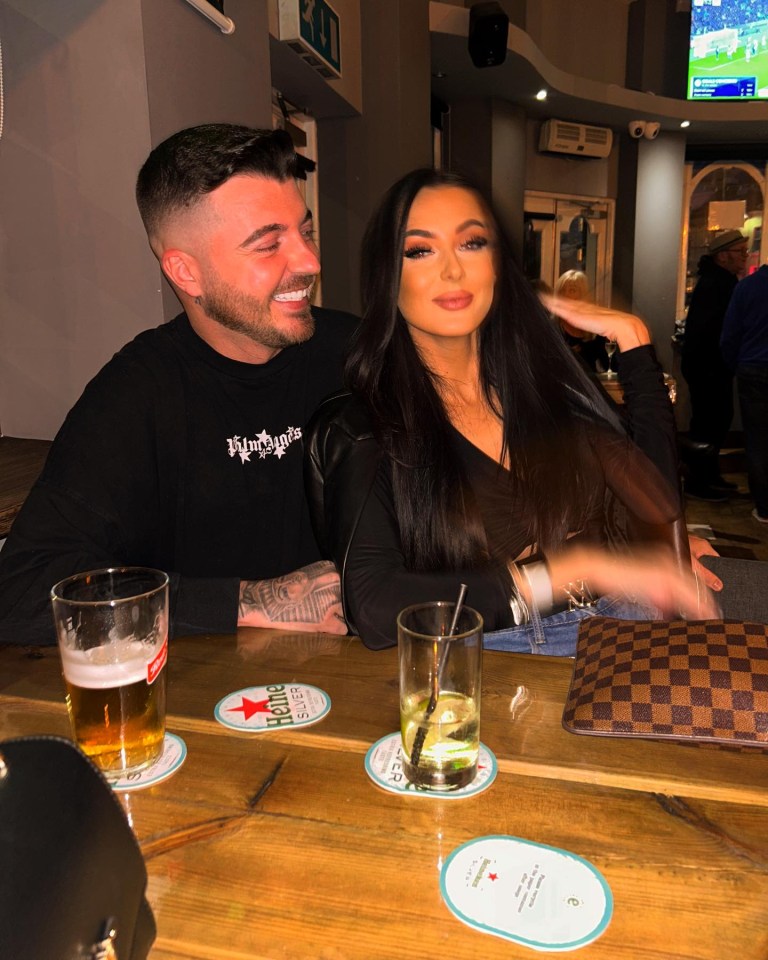 a man and a woman sit at a bar with a heineken beer on a coaster