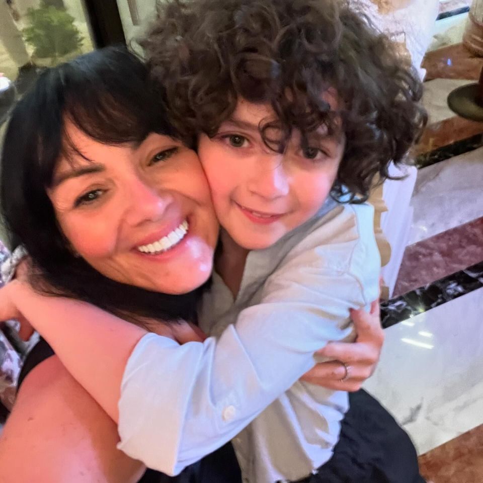 a woman is hugging a young boy with curly hair