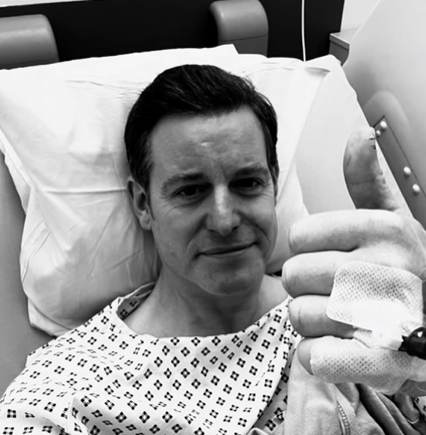 a man in a hospital gown is giving a thumbs up