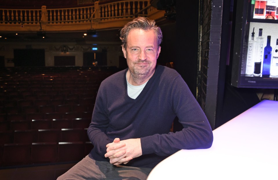 a man in a blue sweater is sitting on a bar