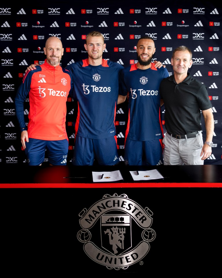 four men standing in front of a manchester united sign