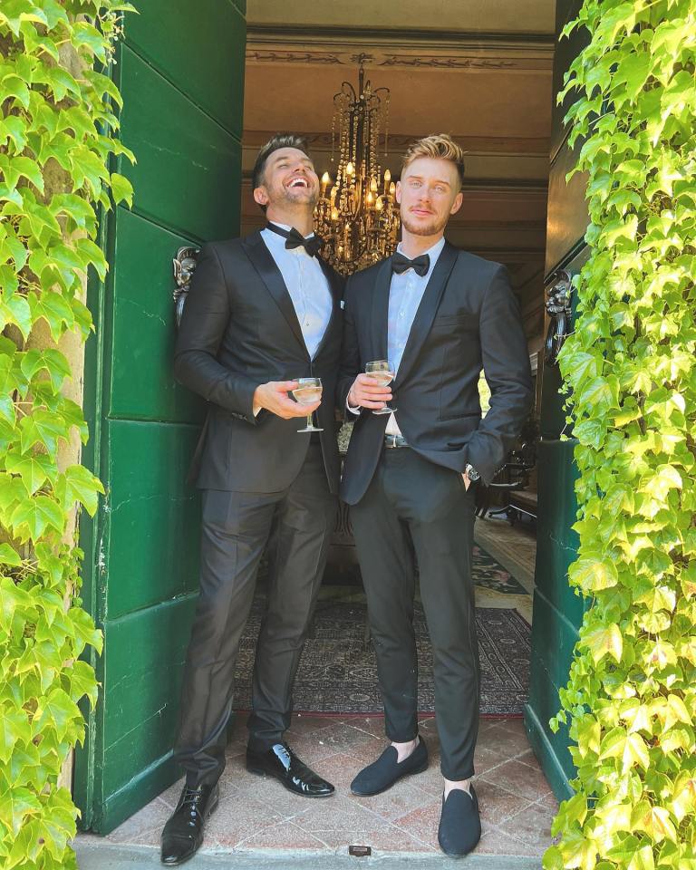 two men in tuxedos standing next to each other in front of a green door