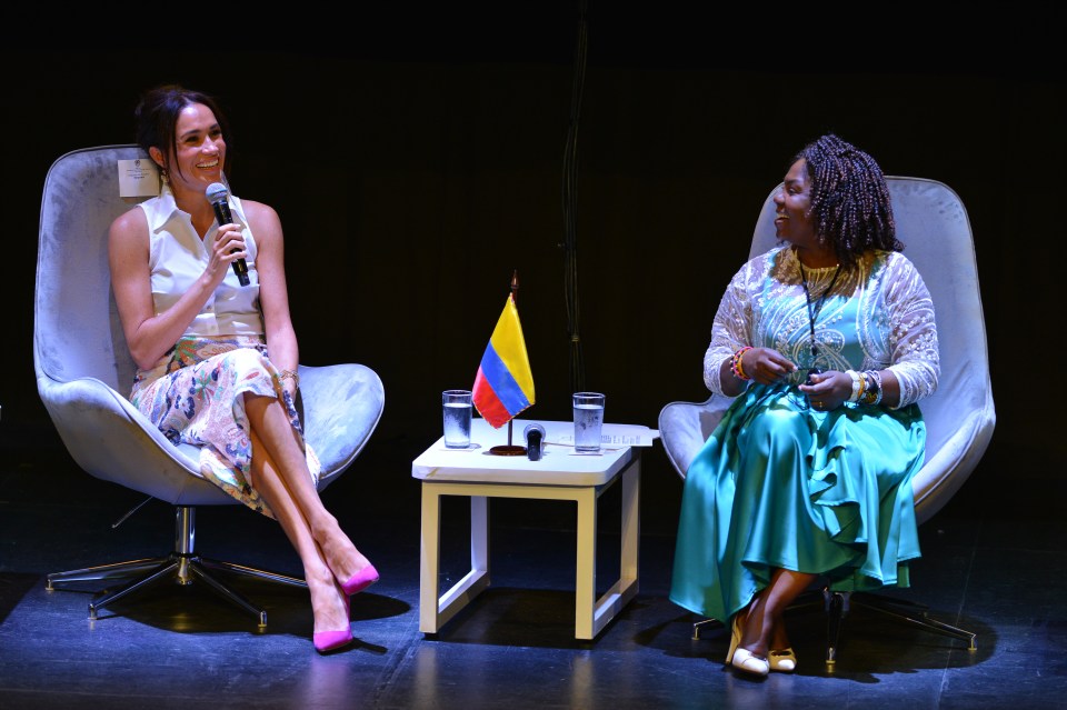 two women are sitting in chairs and one is holding a microphone