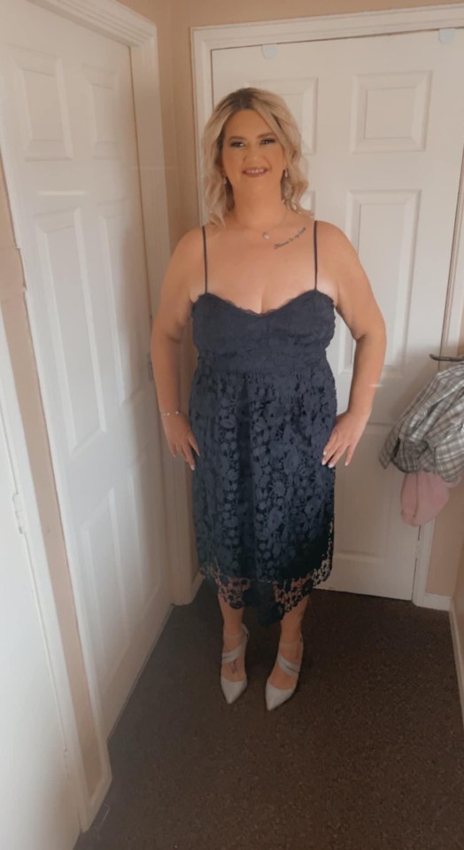 a woman in a blue lace dress stands in a hallway