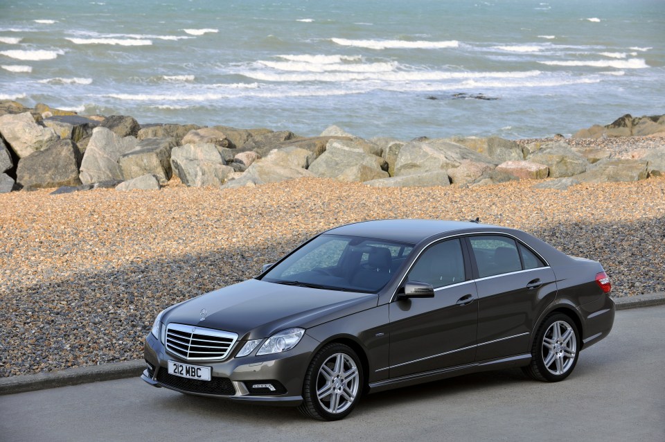 a mercedes is parked on the side of the road near the ocean