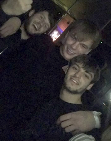 three young men are posing for a picture together in a dark room .