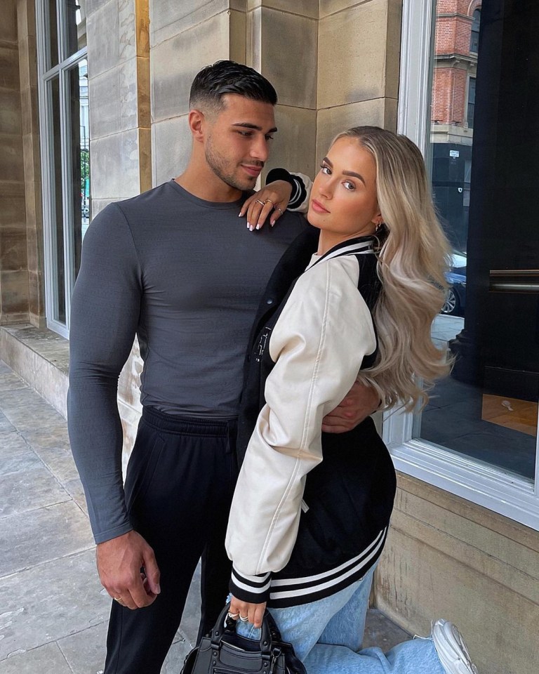 a man and a woman pose for a picture in front of a building