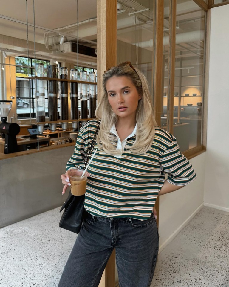 a woman in a striped shirt is holding a cup of coffee