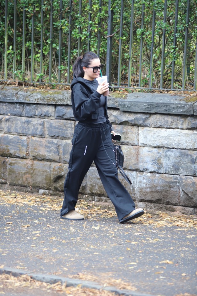 a woman in black sweatpants is walking down the street