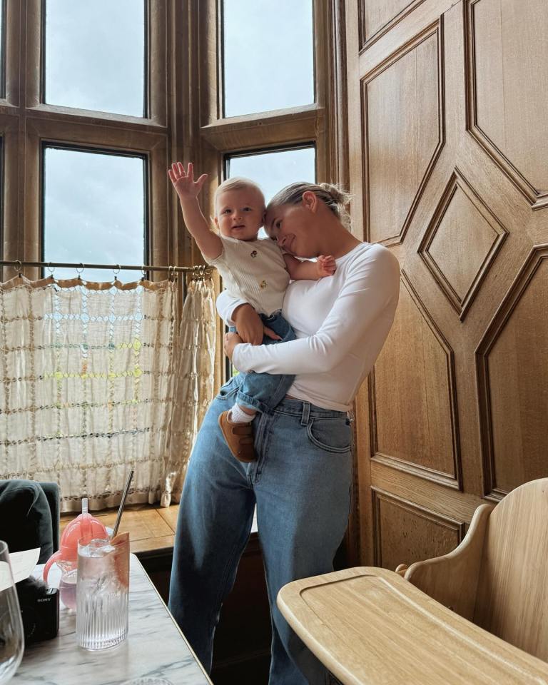 a woman holds a baby in her arms in front of a window