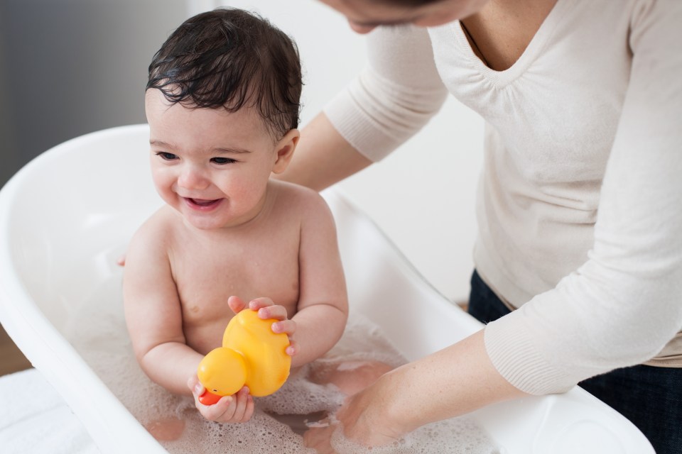 a baby is taking a bath with a yellow rubber duck