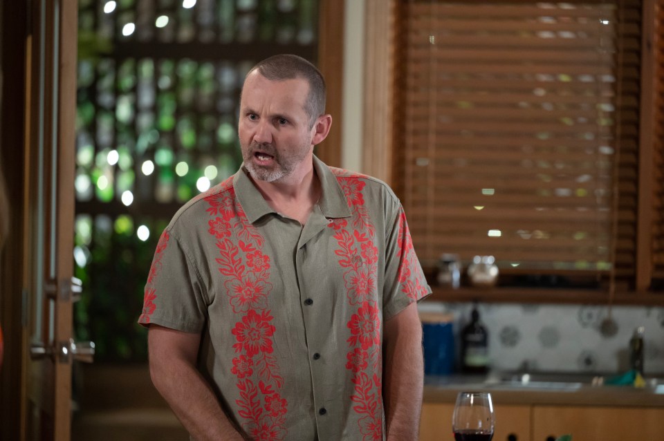 a man in a hawaiian shirt stands in front of a window