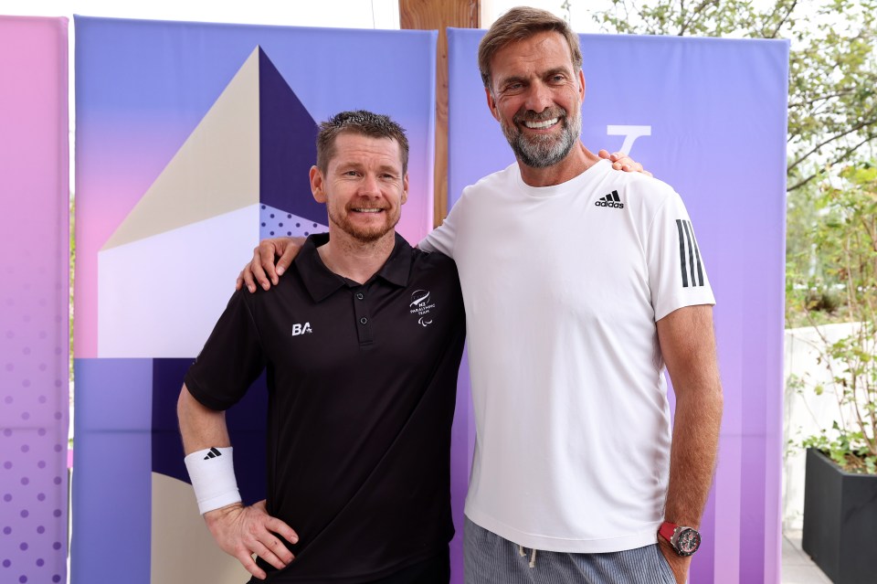 two men posing for a picture with one wearing an adidas shirt