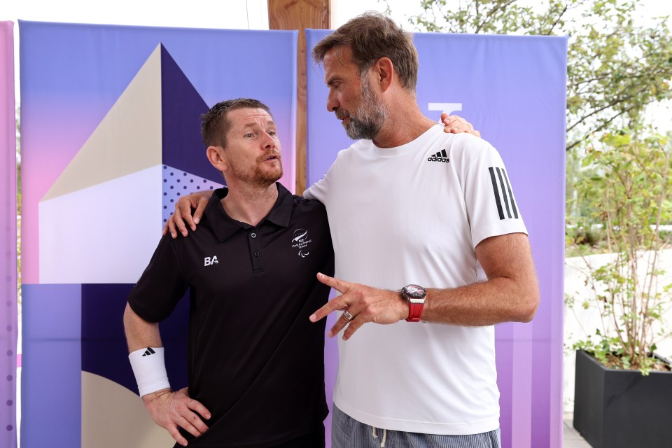 two men standing next to each other with one wearing an adidas shirt