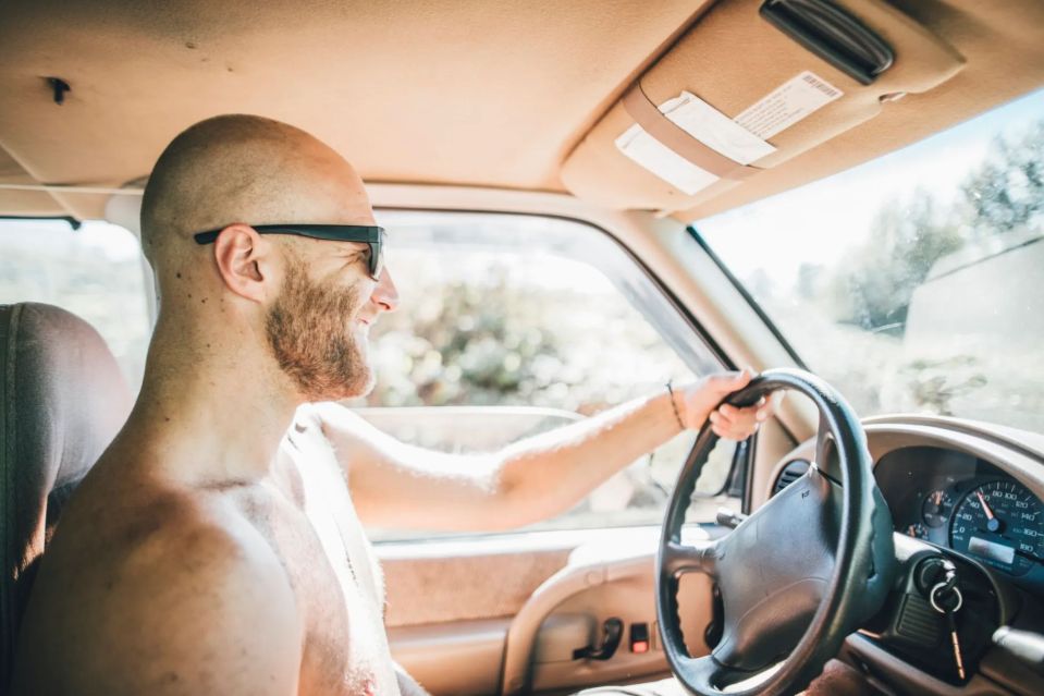 a man wearing sunglasses is driving a car