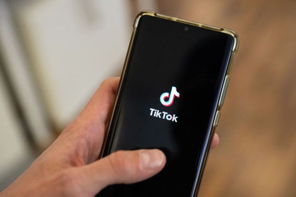 a person is holding a cell phone that says tiktok on the screen