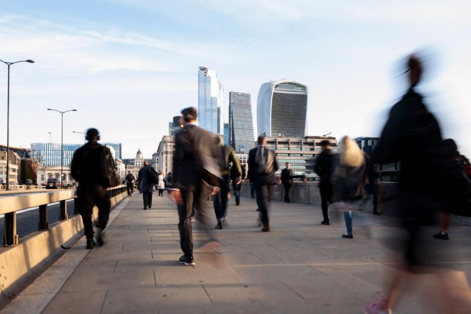 a group of people are walking across a bridge in the city