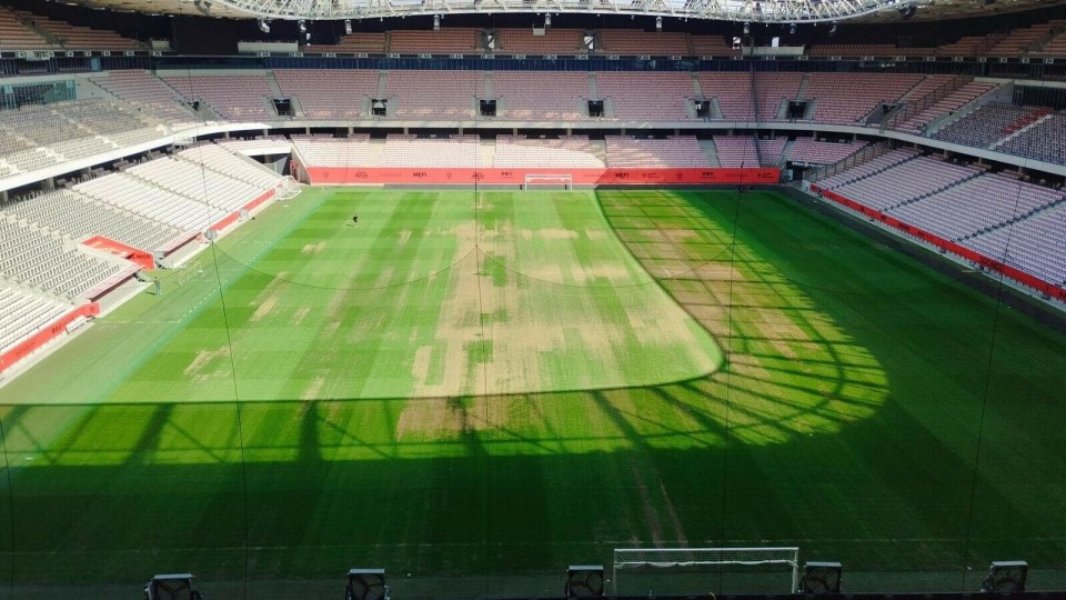 an empty soccer stadium with a shadow on the grass