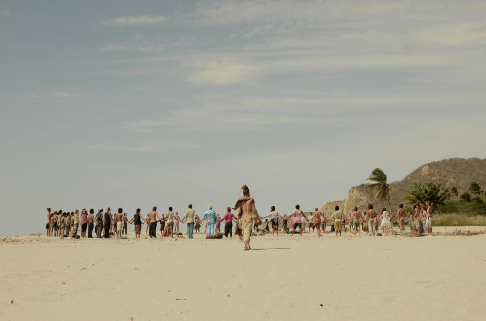 a group of people standing on a beach holding hands