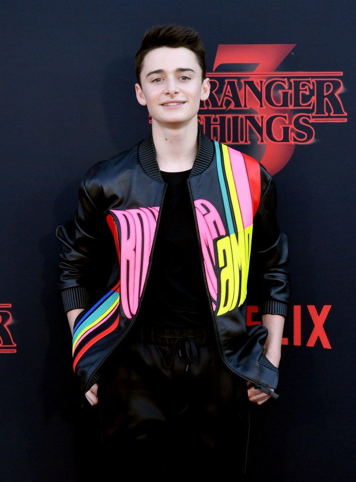 a young man stands on a red carpet that says stranger things