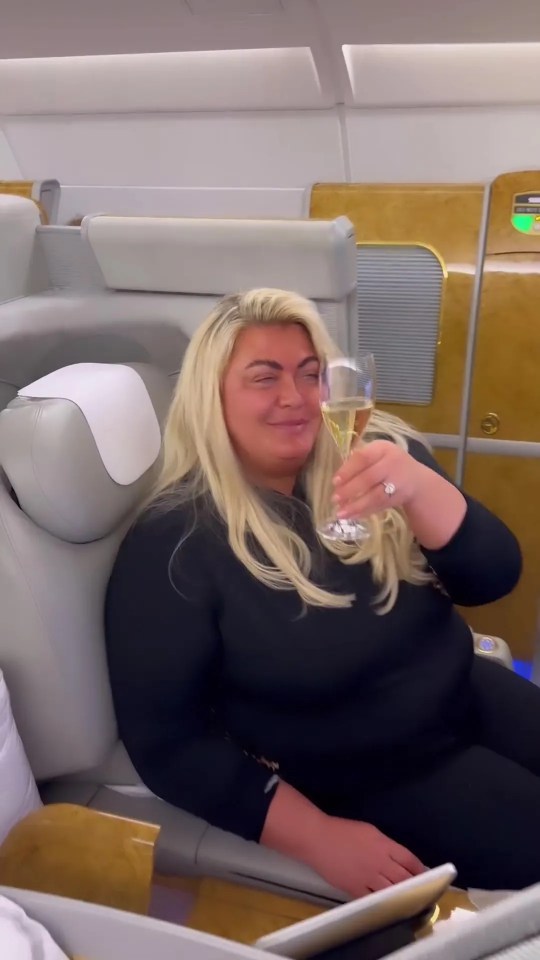 a woman is sitting on an airplane holding a glass of champagne