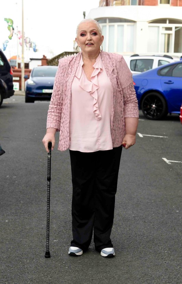 a woman with a cane is standing in a parking lot