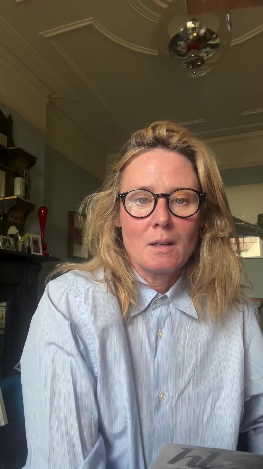 a woman wearing glasses and a blue shirt is reading a newspaper