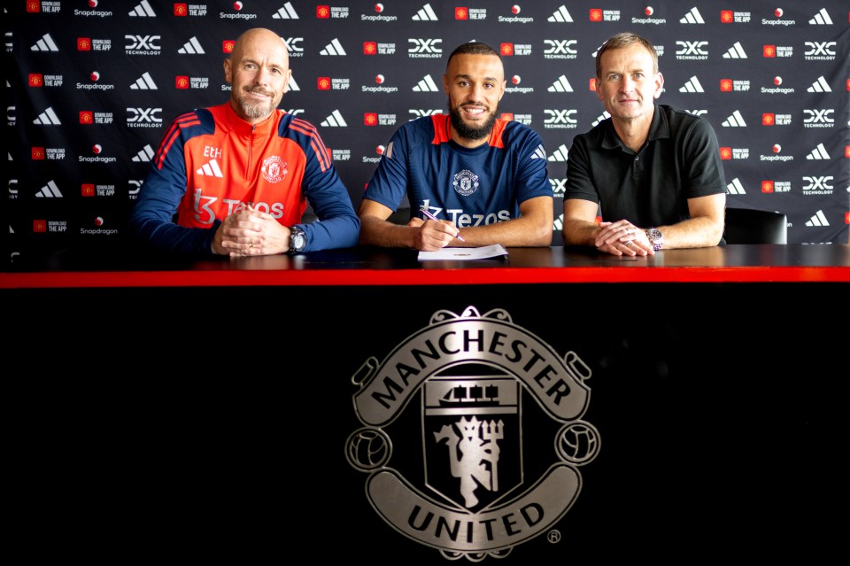 three men sit at a table in front of a manchester united logo