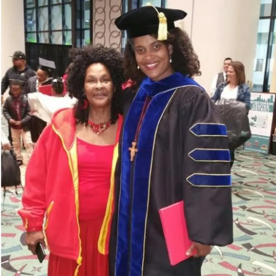 a woman in a graduation cap and gown poses with another woman