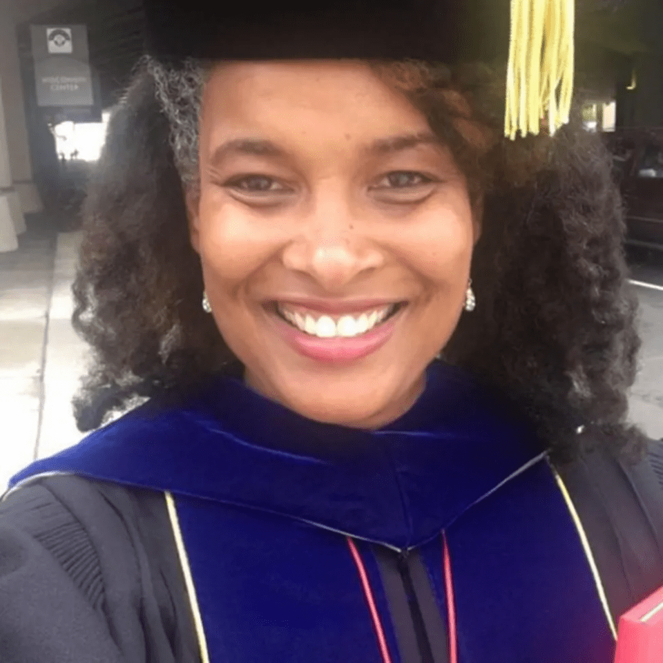 a woman wearing a graduation cap and gown is smiling