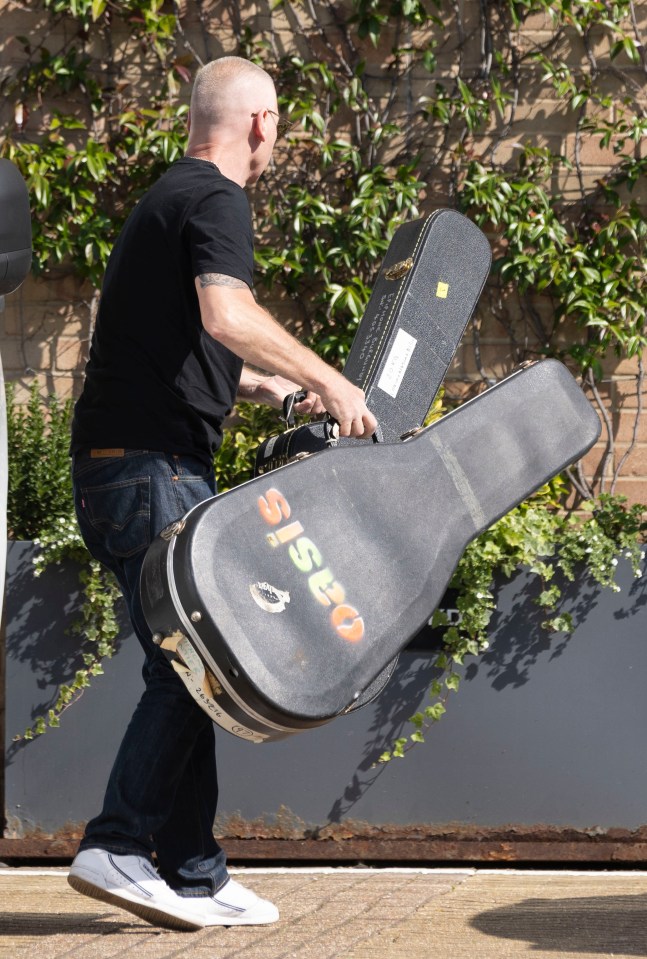 a man carrying a guitar case that says oasis on it