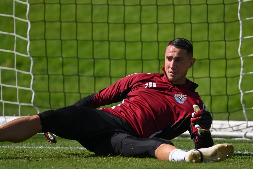 a soccer player wearing a maroon adidas shirt is stretching on the field