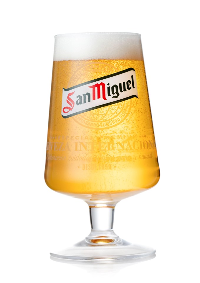 a glass of san miguel beer with foam on top