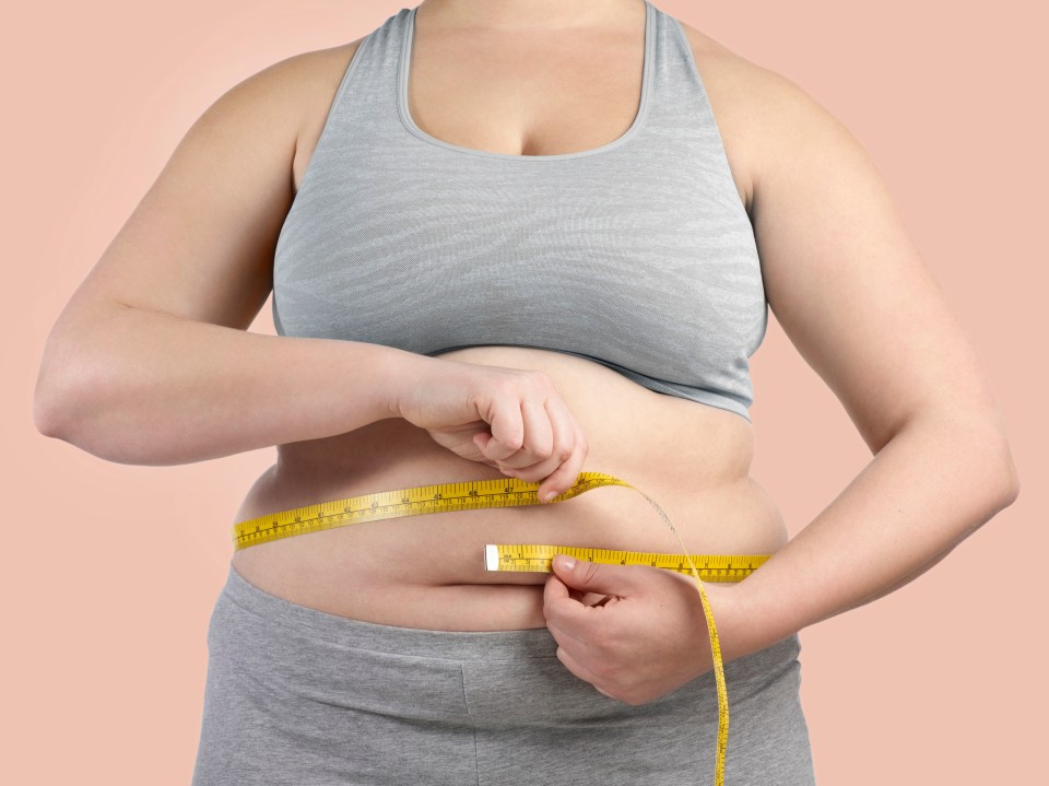 a woman is measuring her waist with a tape measure