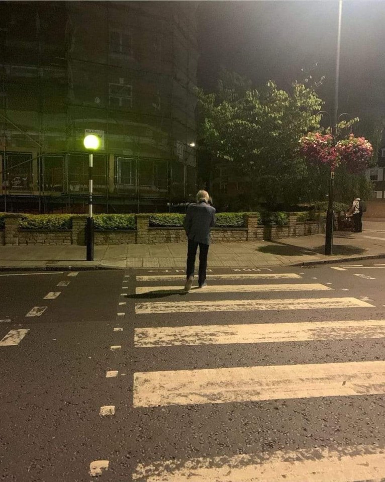 a man walking across a crosswalk at night