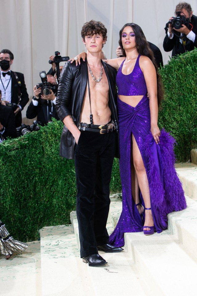 a man without a shirt is standing next to a woman in a purple dress