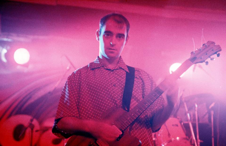 a man in a polka dot shirt is playing a guitar