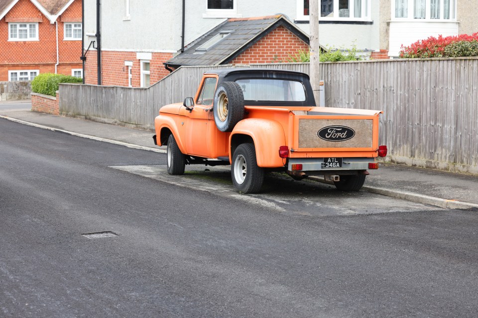 an orange ford truck is parked on the side of the road