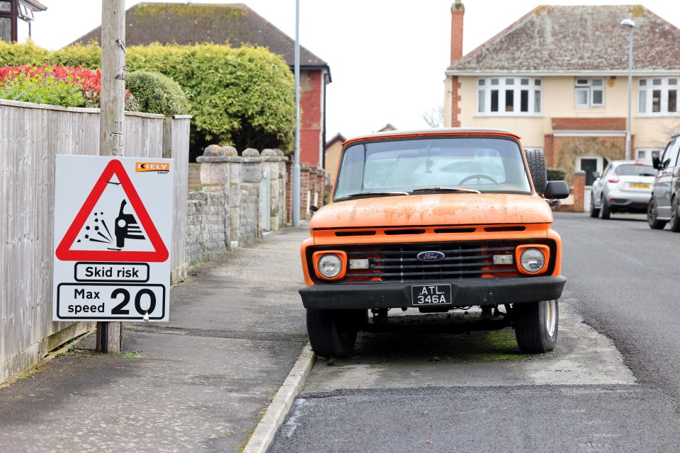 an orange ford truck is parked next to a sign that says skid risk max speed 20