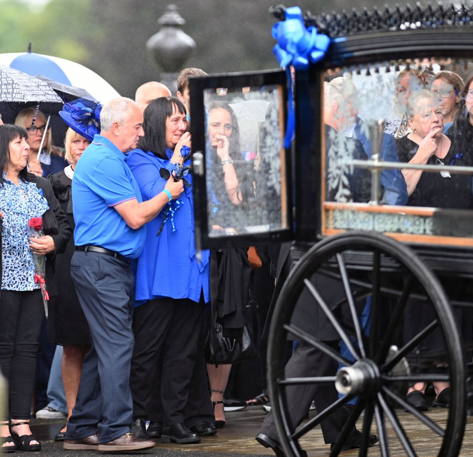 a group of people standing in front of a black carriage