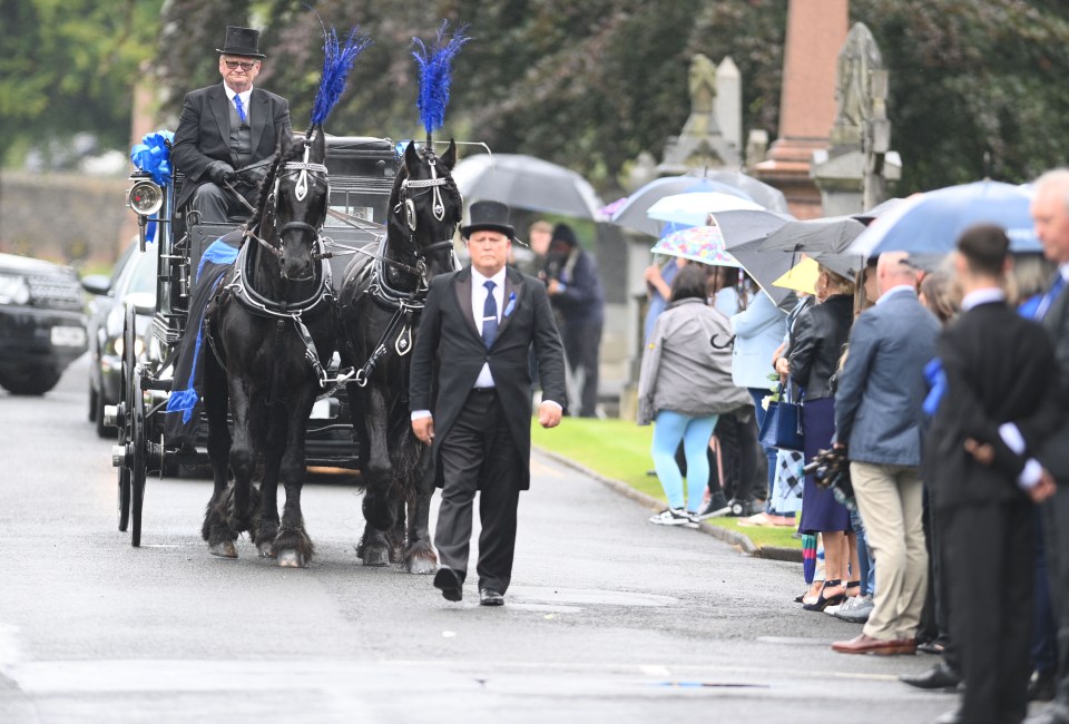 a man in a top hat leads a horse drawn carriage