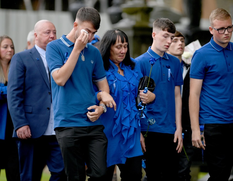 a group of people in blue shirts are walking in a line