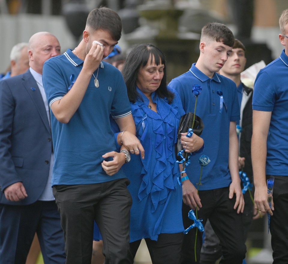 Debbie linked arms with son Zak - Jay's older brother - at his funeral