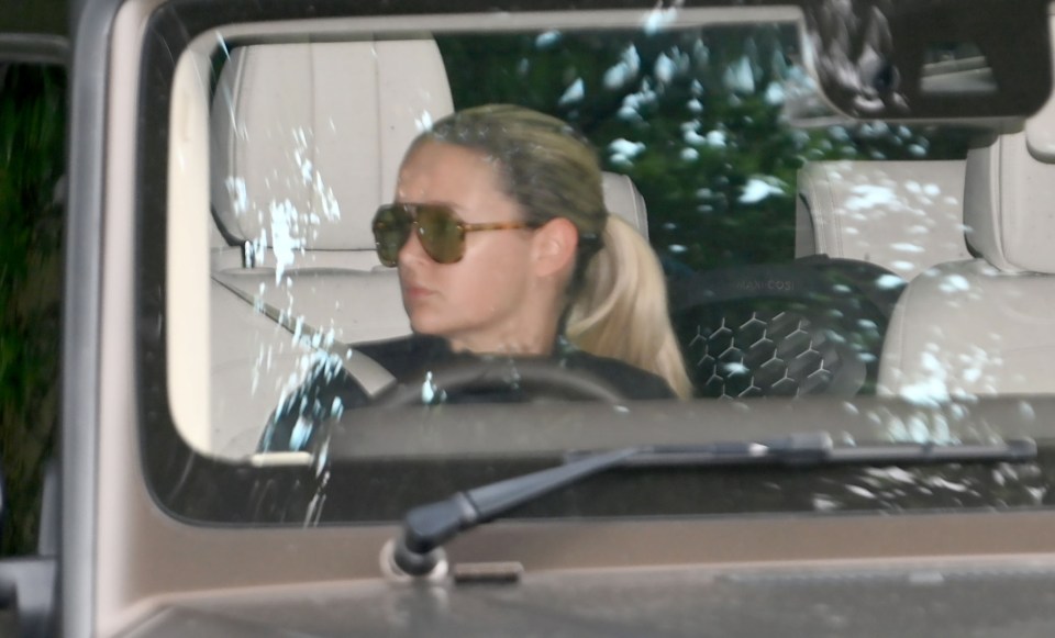 a woman wearing sunglasses sits in the driver 's seat of a car