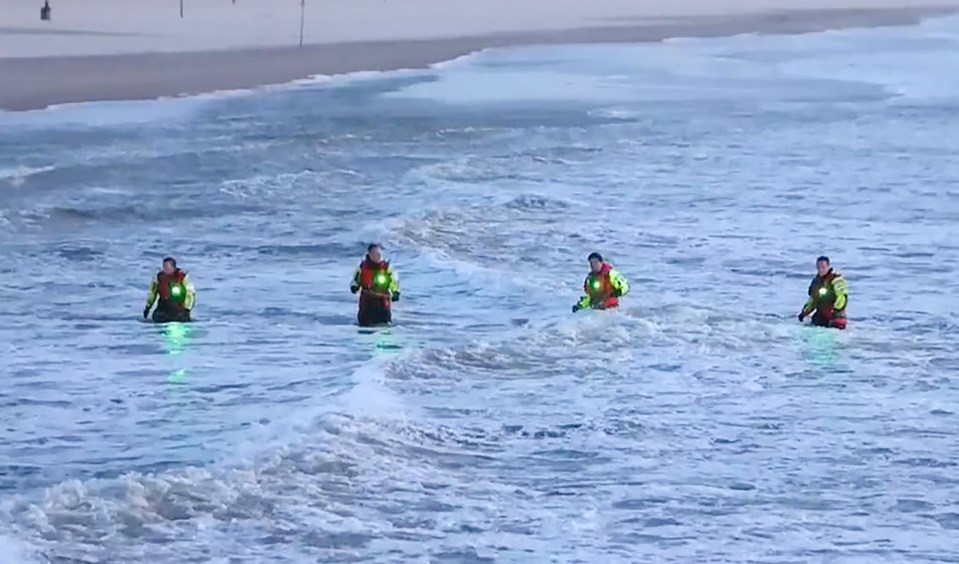 a group of people in life jackets are walking in the ocean